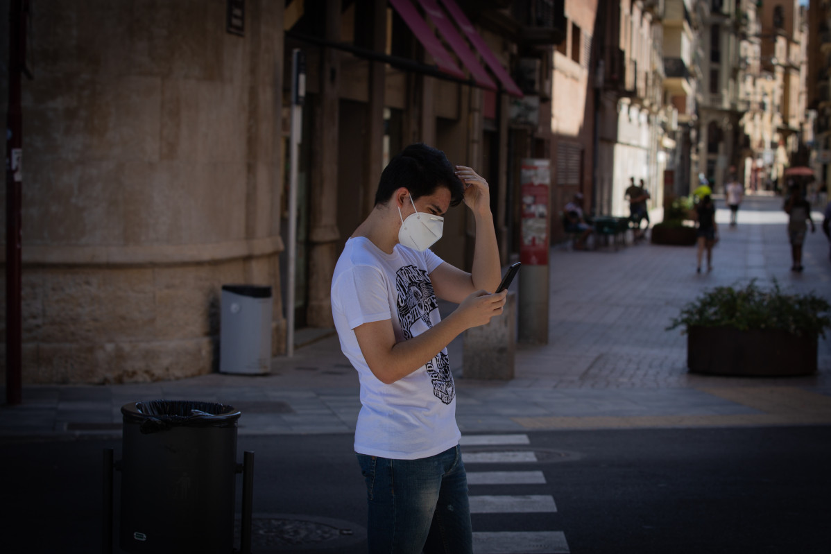Un mozo protexido con máscara camiña por unha rúa do centro de Lleida, capital da comarca do Segrià, en Lleida.