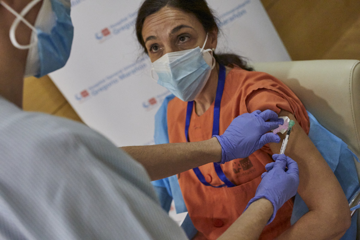 Unha enfermeira vacúa a unha sanitaria contra o coronavirus