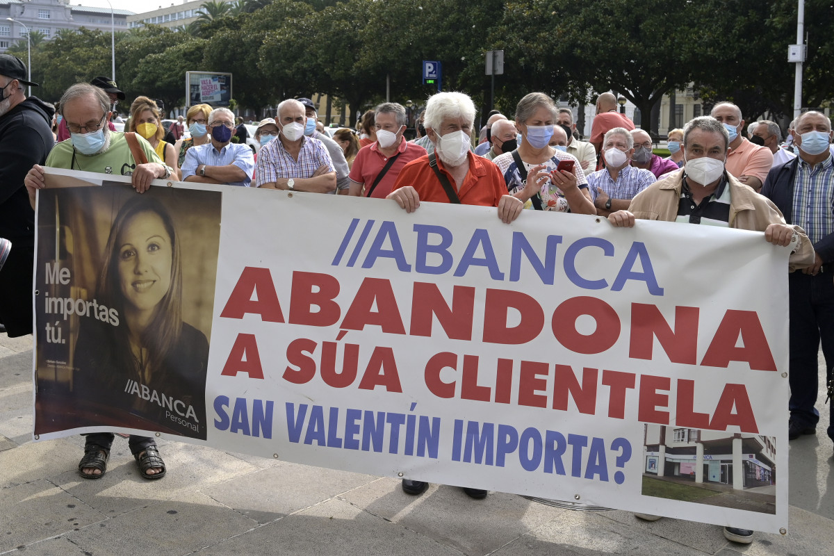 Un grupo de persoas sosteñen unha pancarta durante a manifestación contra o peche de oficinas da entidade Abanca ante a sede de Abanca na Coruña, ao 2 de setembro de 2021, na Coruña, Ga