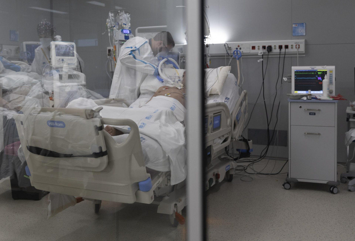 Un sanitario ao redor dun paciente ingresado na UCI do Hospital Enfermeira Isabel Zendal.