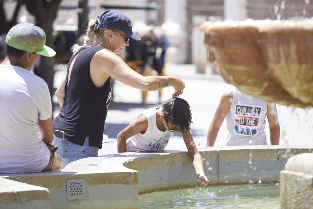 Unha nai bótalle auga ao seu fillo, pola cabeza, na fonte da praza Virxe dos Reyes no primeiro día da segunda onda de calor, ao 7 de xullo de 2022 en Sevilla (Andalucía, España)
