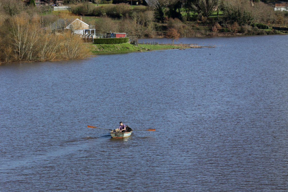 Un batuxo, embarcación tradicional del río Miño, surca las aguas del río Miño tras la crecida, a 2 de enero de 2023, en Portomarín, Lugo, Galicia (España).