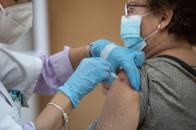 Archivo - Una enfermera vacuna a una mujer contra la gripe y el Covid