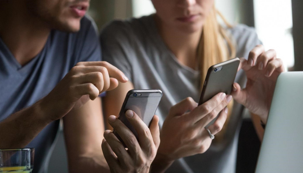 Dos personas utilizan sus teléfonos móviles