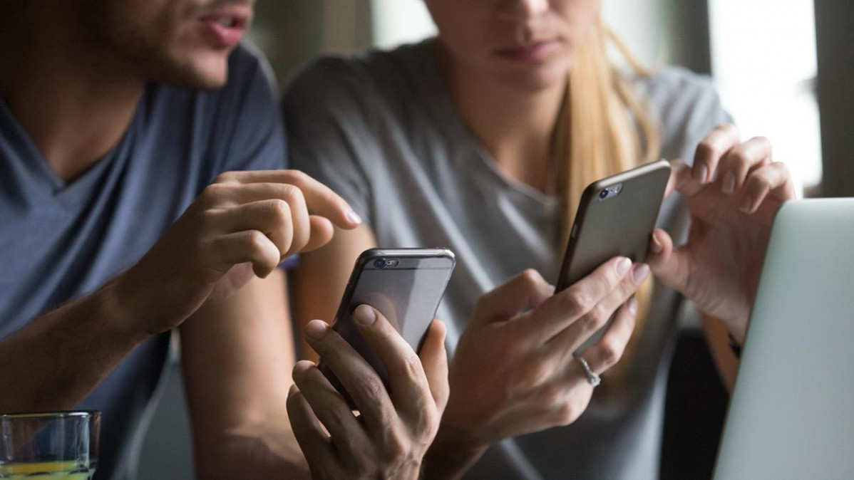 Dos personas utilizan sus teléfonos móviles