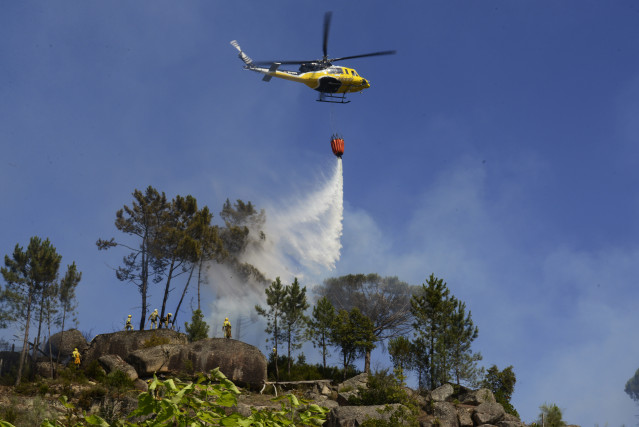 Archivo - Un helicóptero arroja agua sobre un incendio forestal, a 28 de julio de 2021, en la parroquia de Santa Mariña do Monte, Ourense, Galicia (España).