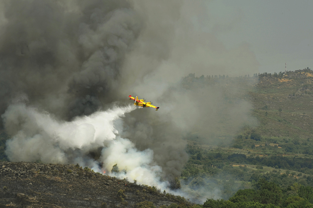 Archivo - Un avión apaga fuegos de la UME sobrevuela y vierte agua sobre el incendio de Cualedro (Ourense) que sigue sin control desde su inicio el miércoles y que se ha convertido ya en el peor del