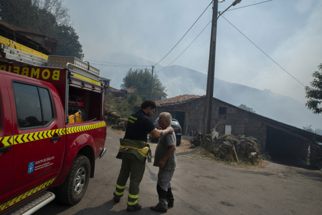 Un residente y un bombero después de la noche con el fuego alrededor de la aldea, a 10 de agosto de 2025, en Maceda, Ourense, Galicia (España).