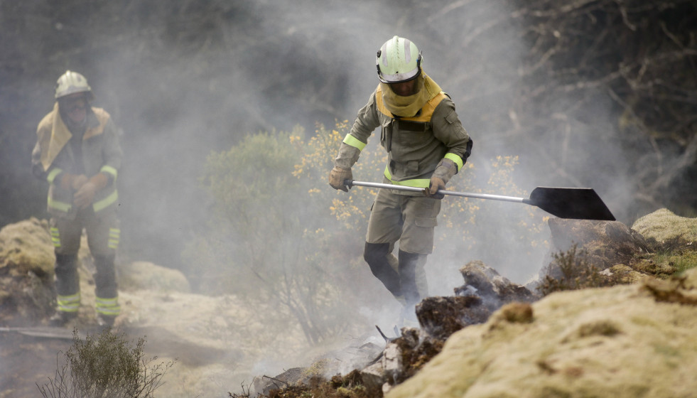 Archivo - Dos brigadistas forestales trabajan para extinguir las llamas en un incendio forestal