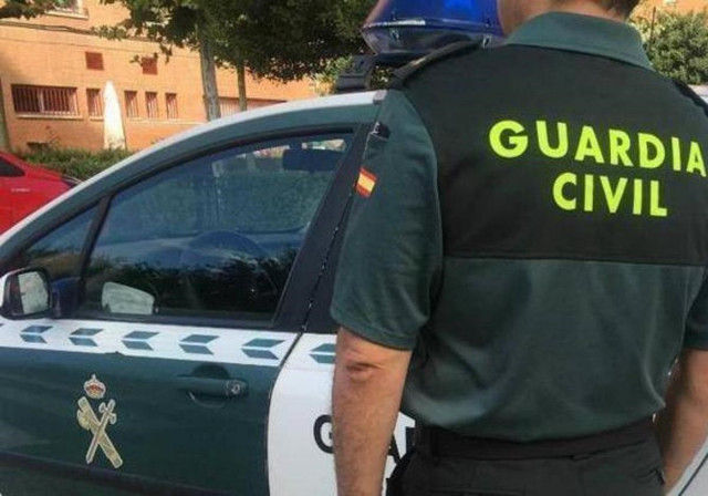 Archivo - Imagen de archivo de un agente de la Guardia Civil ante un coche patrulla