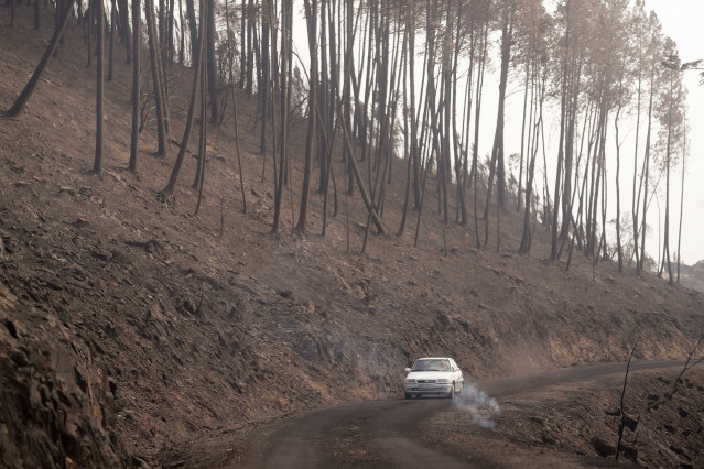 Un coche circula al lado del terreno calcinado, a 20 de septiembre de 2025, en A Barca, Sober, Lugo, Galicia (España).