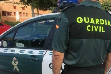 Archivo - Imagen de archivo de un agente de la Guardia Civil ante un coche patrulla