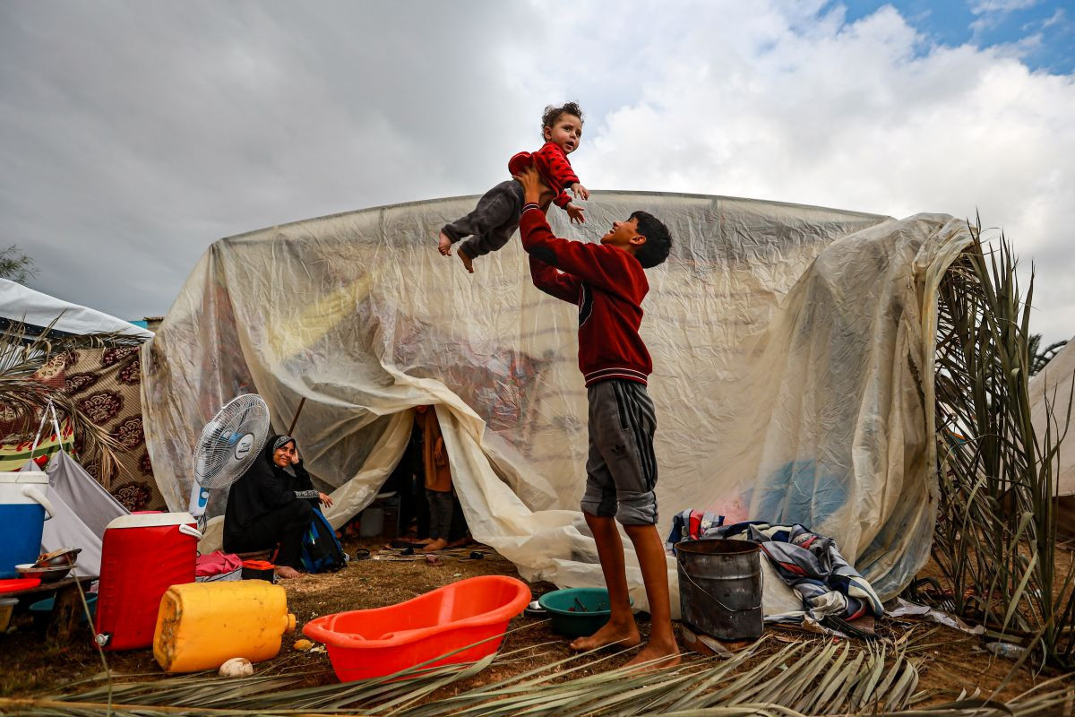 Un niño palestino juega con su hermano junto en un campo de desplazados en Gaza.