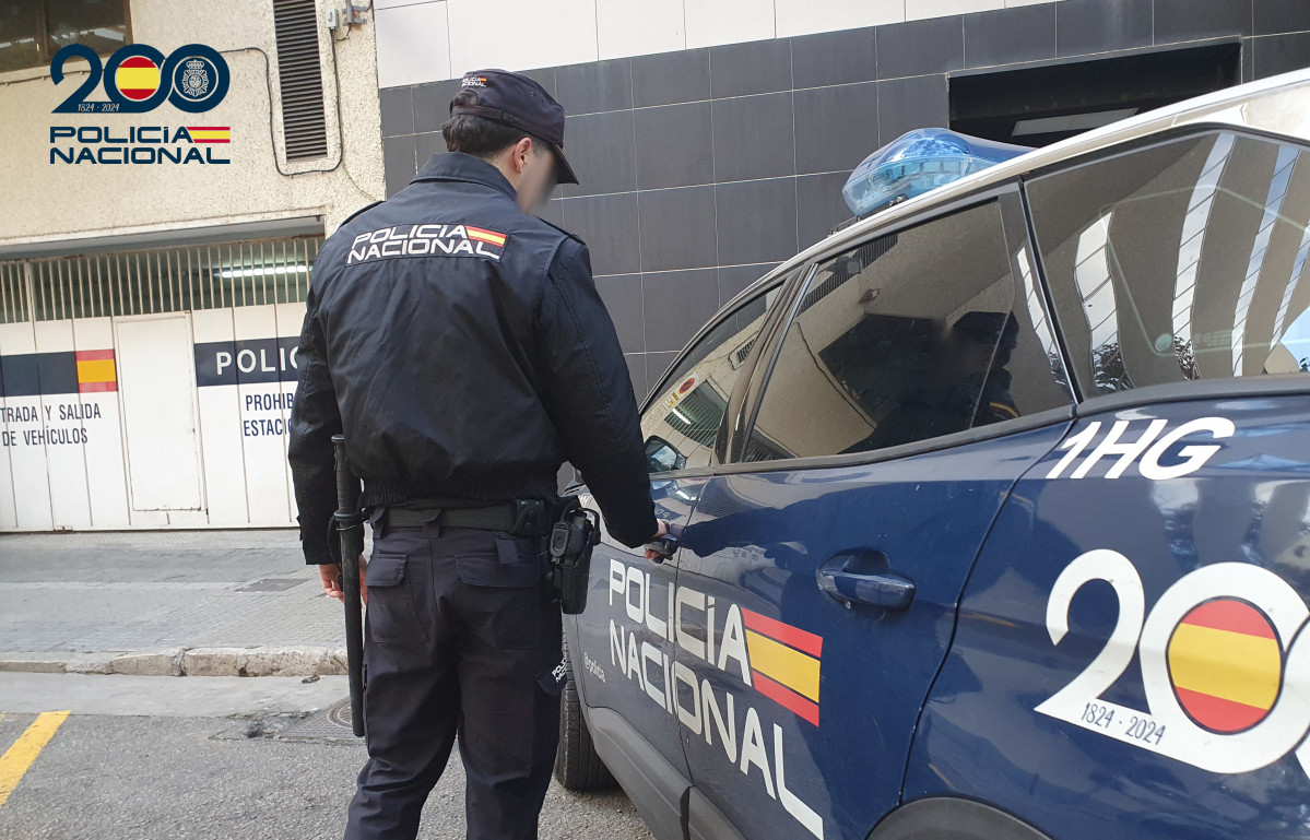 Un agente de la Policía Nacional frente a un coche patrulla.