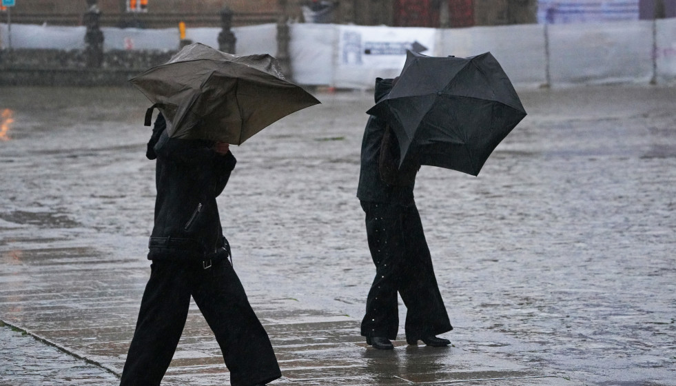 Varias personas intentan sujetar sus paraguas, a 26 de enero de 2026, en Santiago de Compostela, A Coruña, Galicia (España).