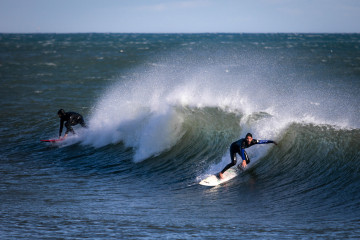Archivo - Dos surfistas surfean una ola en la playa de Bogatell, a 17 de enero de 2023, en Barcelona, Catalunya (España). El séptimo gran temporal de la temporada ha traído viento, oleaje, nevadas