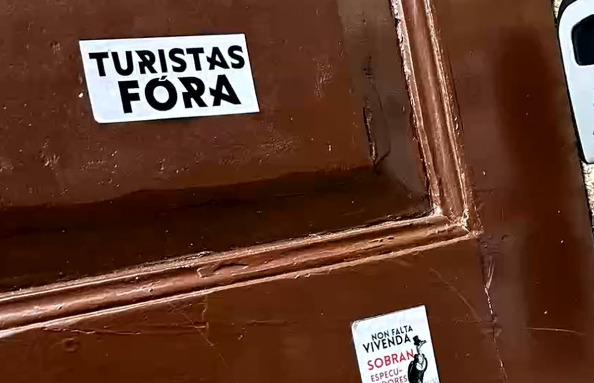 Pegatinas contra los turistas en una de las puertas de un establecimiento saboteado en Santiago
