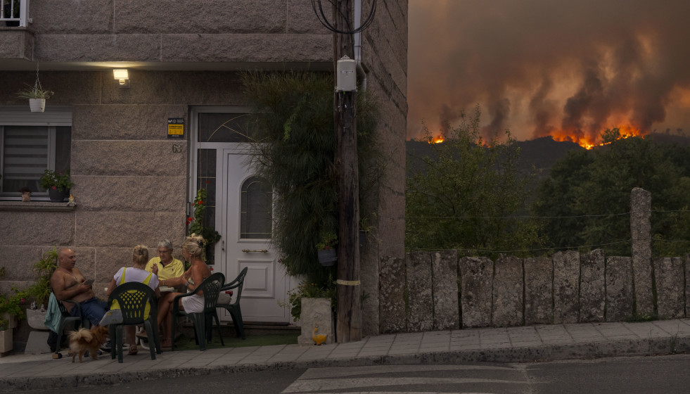 Archivo - Un grupo de personas juega a las cartas mientras avanza el incendio forestal en Carballeda de Avia, Galicia, noroeste de España.
