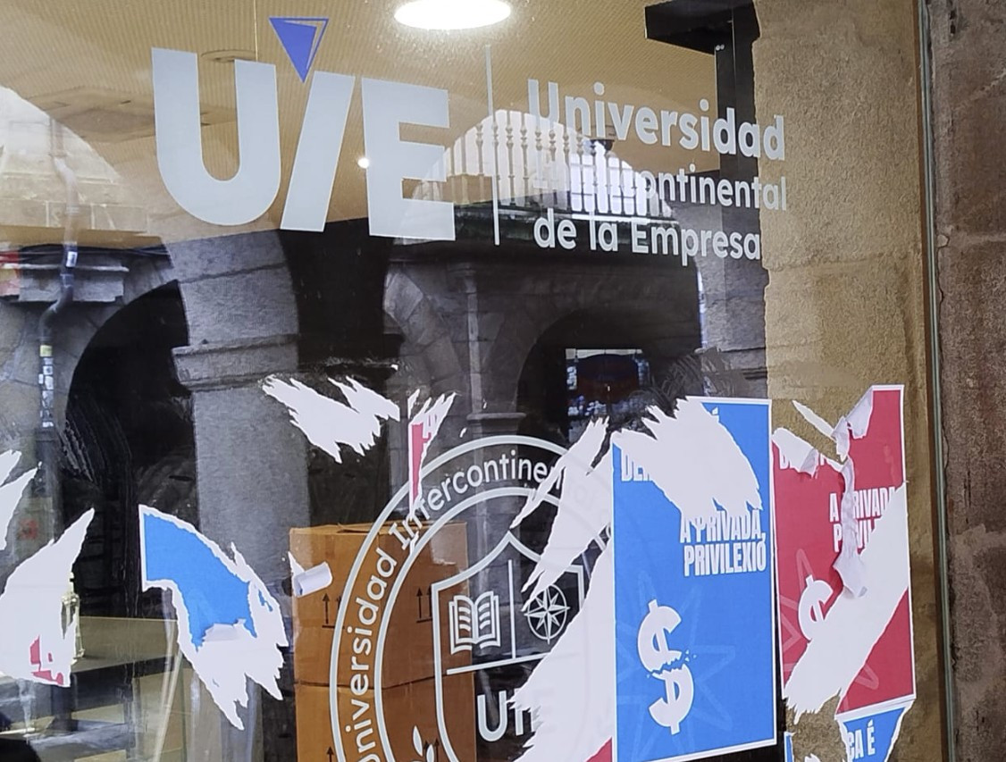 Restos de carteles en la vidriera de la sede de la UIE en Santiago de Compostela