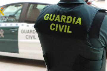 Archivo - Un agente de la Guardia Civil junto a un vehículo oficial.