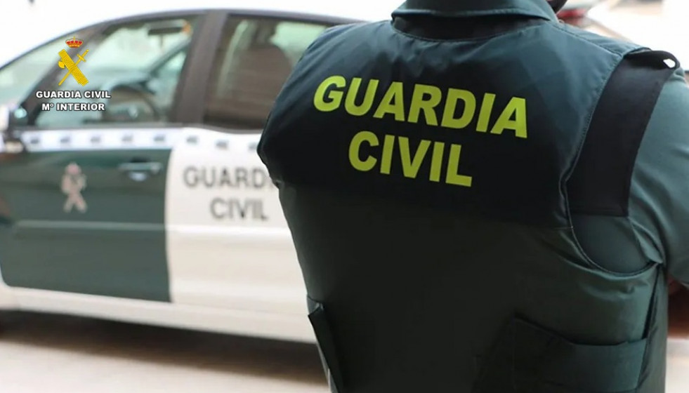 Archivo - Un agente de la Guardia Civil junto a un vehículo oficial.