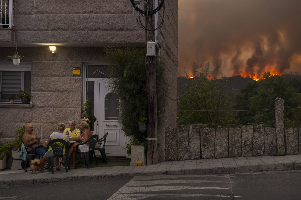 Archivo - Un grupo de personas juega a las cartas mientras avanza el incendio forestal en Carballeda de Avia, Galicia, noroeste de España.