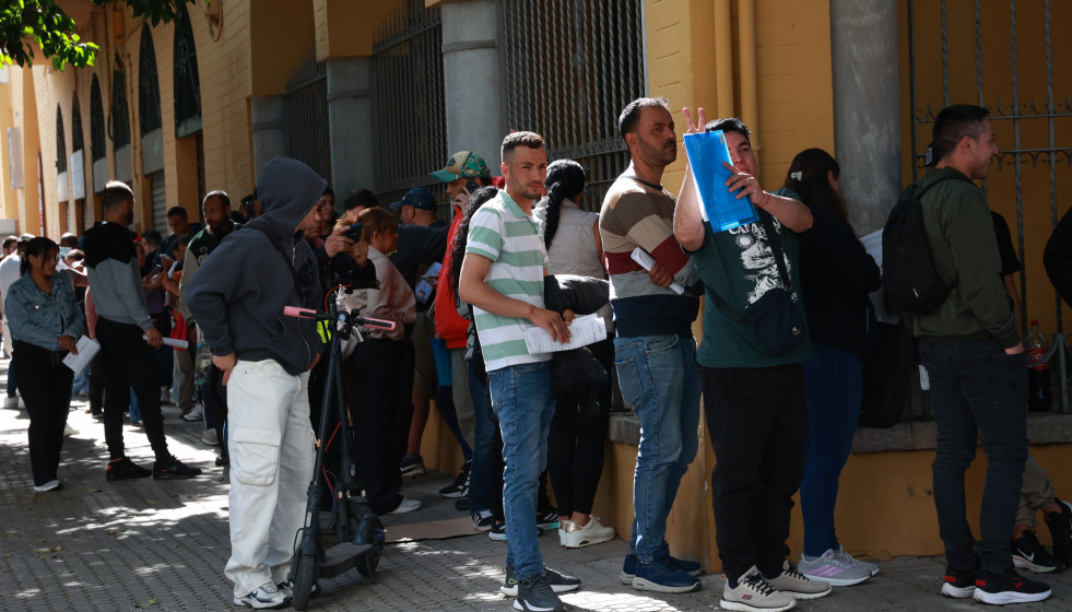 Personas migrantes hacen cola para la tramitación de su regularización administrativa en Sevilla.