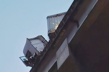 Cabina del camión con la puerta abierta colgando sobre el viaducto