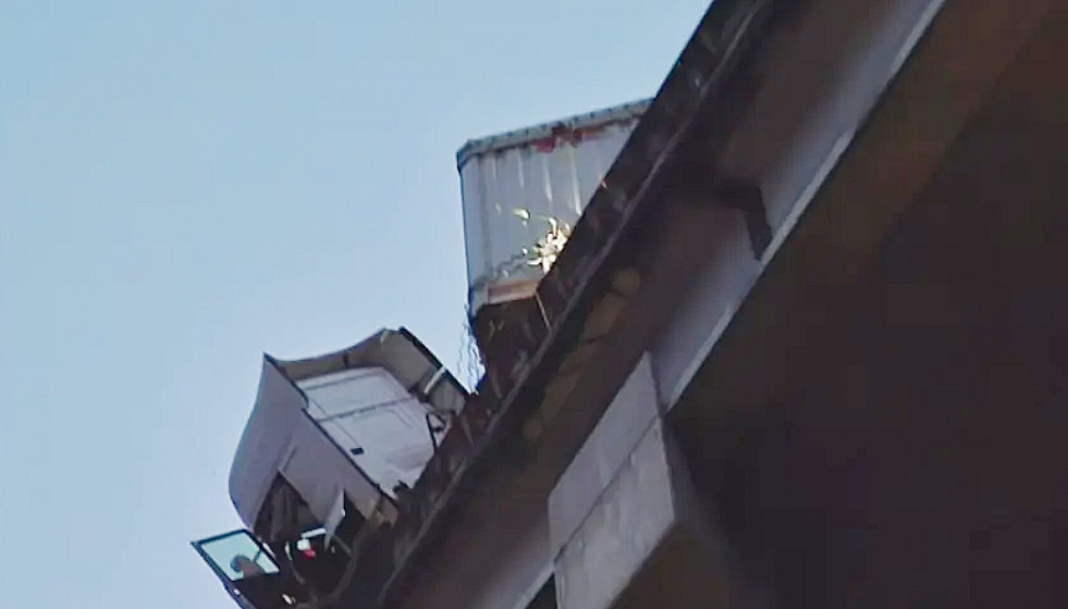 Cabina del camión con la puerta abierta colgando sobre el viaducto