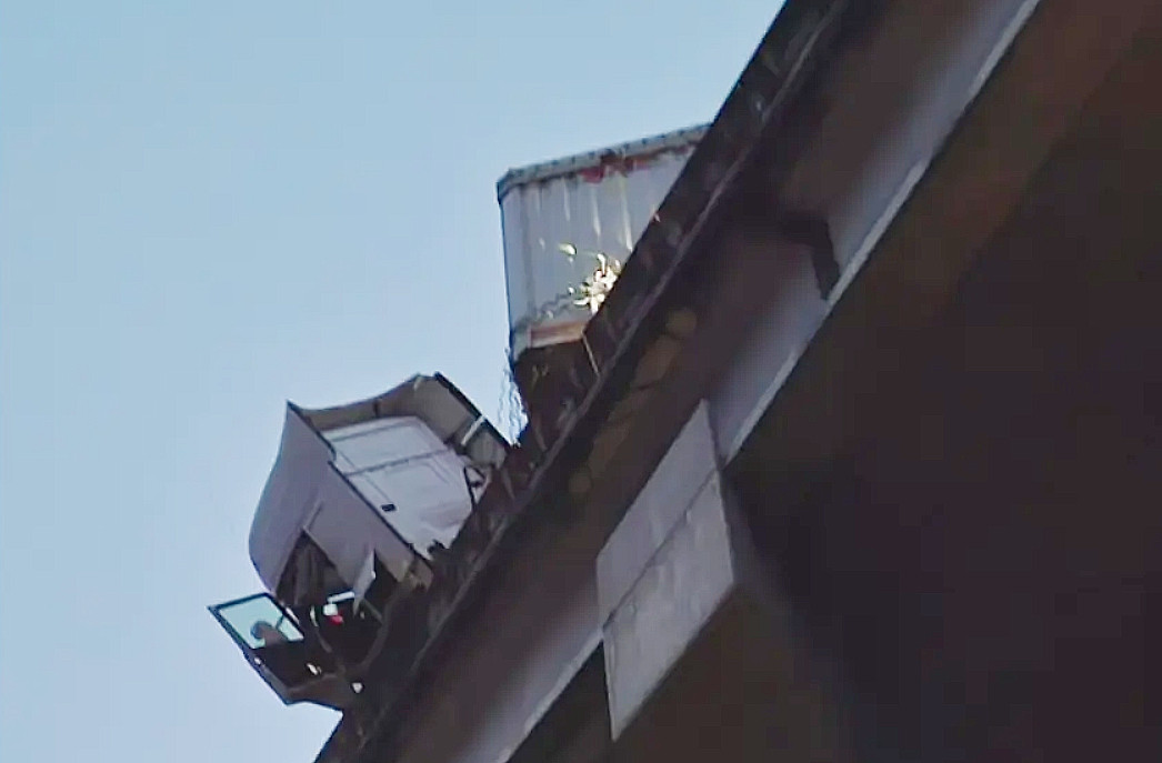 Cabina del camiu00f3n con la puerta abierta colgando sobre el viaducto