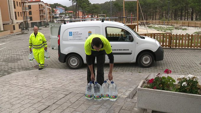 Operarios do Concello de Corme repartindo auga em botella