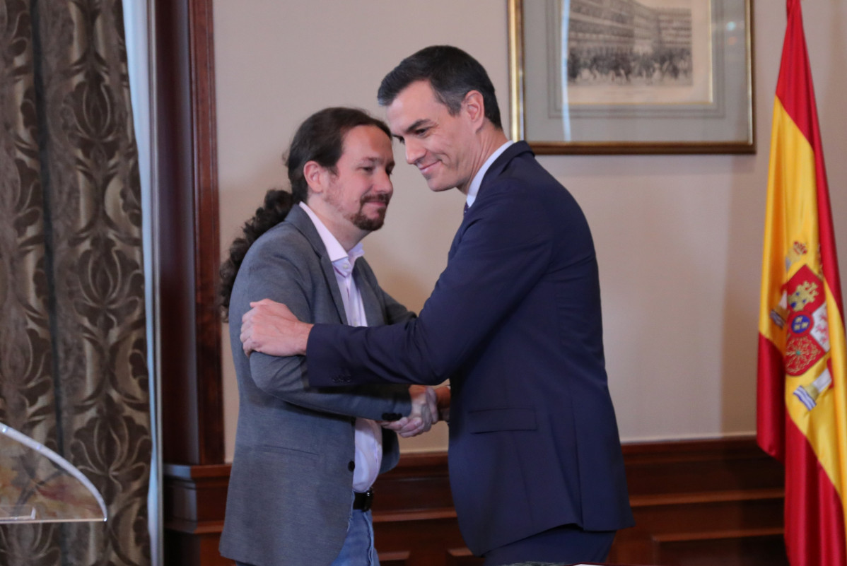 O presidente do Goberno en funcións, Pedro Sánchez e o líder de Podemos, Pablo Iglesias, abrázanse no Congreso dos Deputados despois de asinar o principio de acordo para compartir un 
