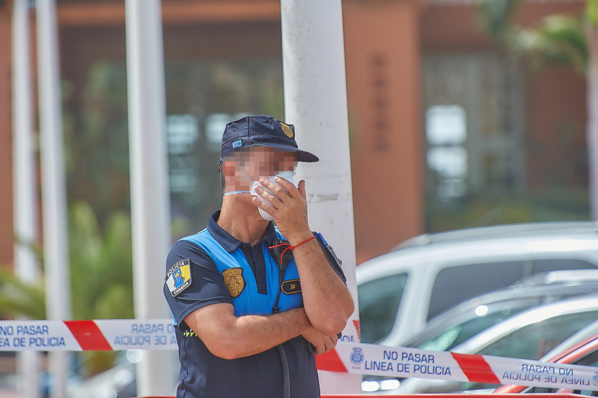 Un policu00eda protéxese cunha máscara mentres custodia o Hotel H10 Costa Adeje Palace
