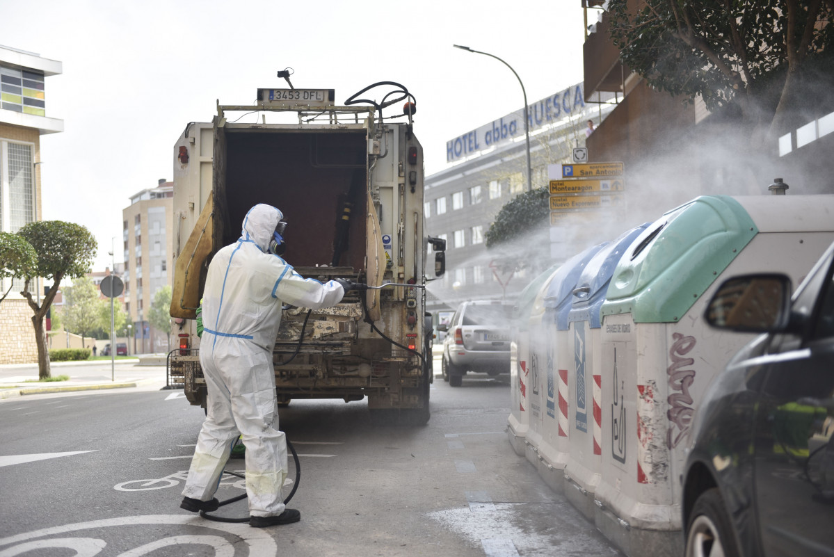 Un traballador protexido de corpo enteiro desinfecta os cubos de lixo e de reciclaxe no cuarto día laborable do estado de alarma por coronavirus, en Huesca, Aragón (España), ao 19 de marzo de 2020.
