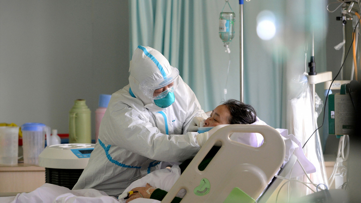 Un médico militar atende a un paciente enfermo de coronavirus na unidade de coidados intensivos, en China.