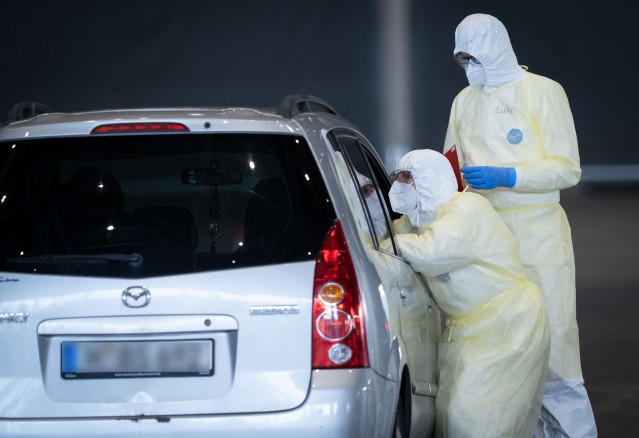 31 March 2020, Lower Saxony, Hanover: Doctors take a smear test from people inside their car at the newly installed Coroa Drive-In test centre on the Hanover exhibition grounds. Photo: Peter Steffen/dpa