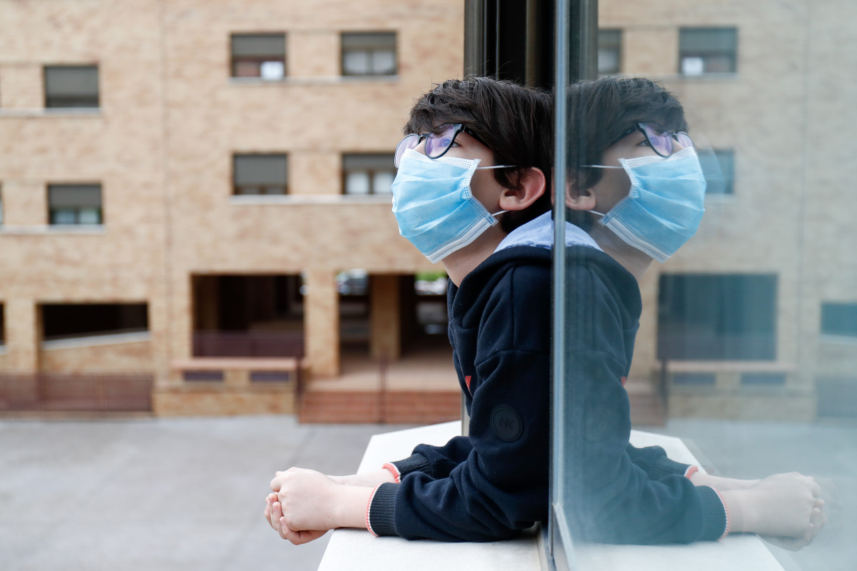 Un neno cunha máscara asómase á xanela da súa casa durante o confinamento polo coronavirus, en Valdemoro/Madrid (España) ao 20 de abril de 2020.