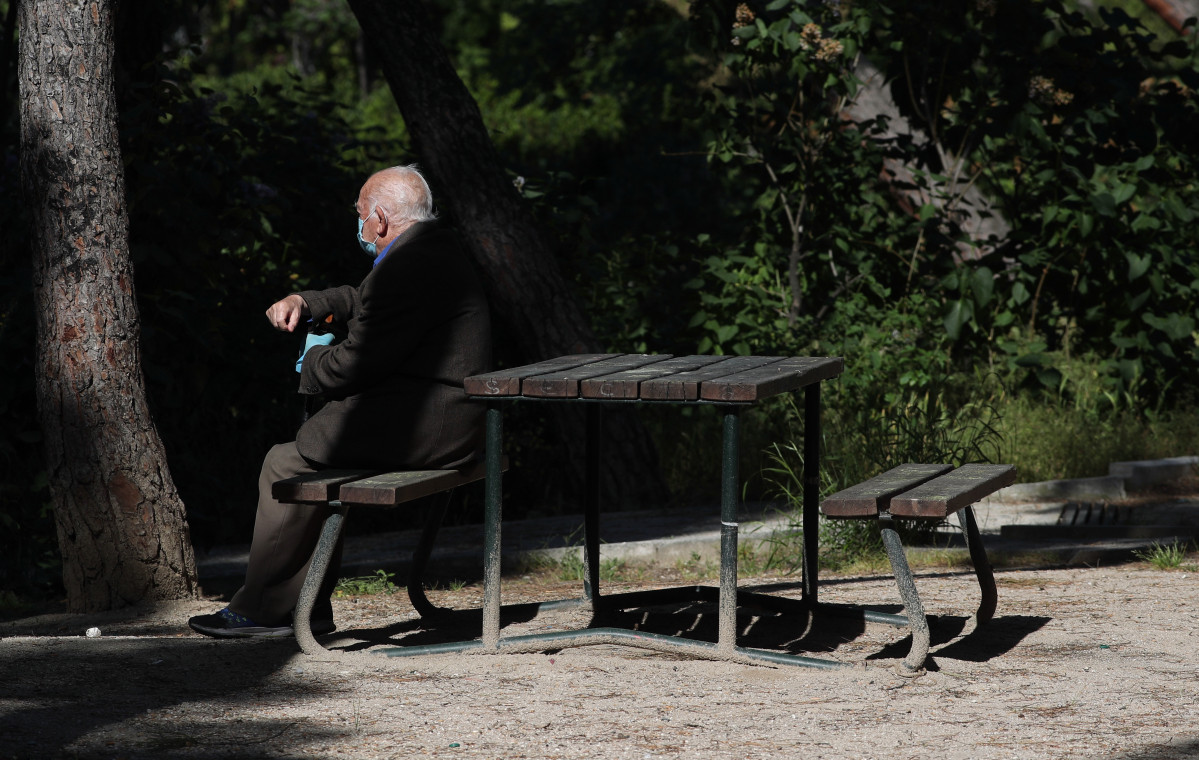 Un ancián con máscara descansa no Parque Calero, no distrito de Ciudad Lineal da capital, un dos que o Concello de Madrid abriu e nos que se permite pasear e facer ejerci