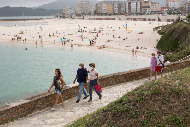 Cidadáns pasean xunto á praia de Rapadoira de Foz, na comarca galega da Mariña (Lugo).