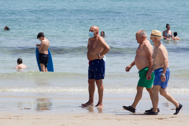 Tres homes protexidos con máscaras pasean pola Praia da Rapadoira en Foz, na comarca da Mariña, Lugo, Galicia (España), ao 9 de xullo de 2020