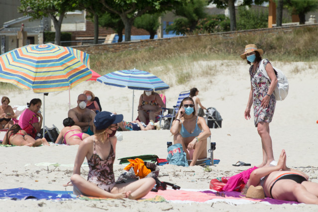Varias persoas protexidas con máscaras toman o sol na Praia da Rapadoira en Foz, na comarca da Mariña, Lugo, Galicia (España), ao 9 de xullo de 2020. O pasado 5 de xullo a Xunta ordenou o peche ata mañá 10 de xullo dos accesos do