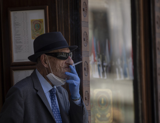 Un home con máscara e luvas fumando un cigarro durante o quinto día da fase 2 en Sevilla (Andalucía, España), ao 29 de maio de 2020.