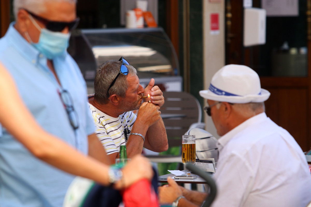 Persoas fumando en terrazas e vías públicas  durante o día no que se decretou a prohibición de fumar en espazos públicos se non se respecta a distancia de seguridade establecida. Málaga