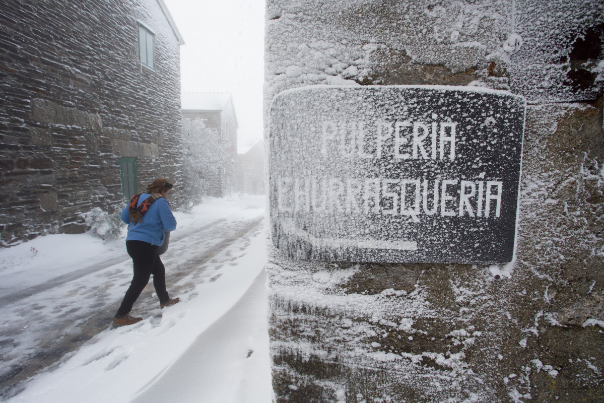 Unha veciña da localidade camiña entre a neve polas callejuelas do municipio de Pedrafita do Cebreiro, en Lugo-País Vasco (España), ao 17 de decembro de 2019.