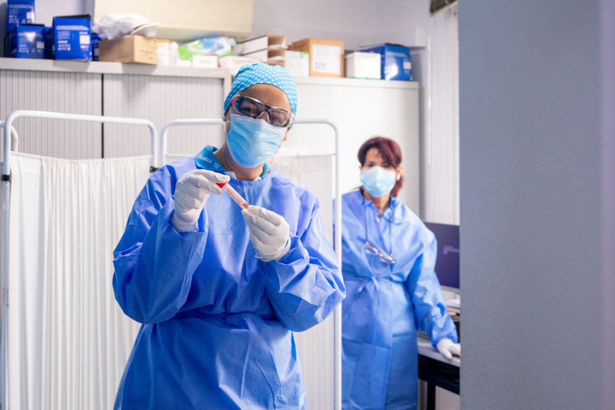Un traballador sanitario protexido sostén unha das probetas utilizadas para a realización de tests PCR .