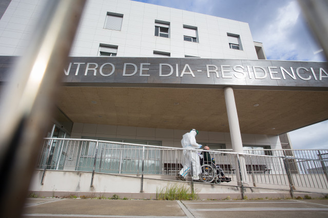 Un traballador sanitario totalmente protexido acoden a buscar a un ancián da residencia de anciáns de San Cibrao onde se orixinou un brote de Covid-19, en San Cibrao, Lugo, Galicia, (España), ao 9 de novembro de 2020. No centro a situación ac