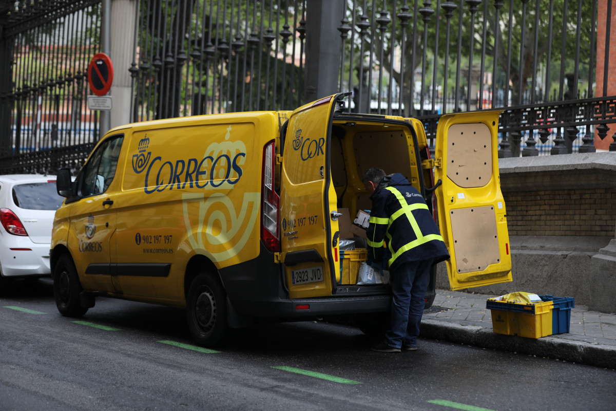 Un traballador de Correos extrae da súa furgoneta paquetes e cartas