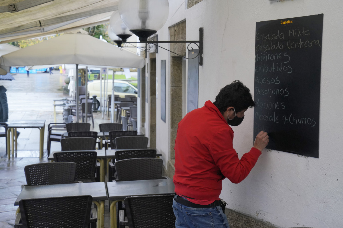 Un home escribe na lousa dun mesón, en Santiago de Compostela, A Coruña, Galicia (España), ao 4 de decembro de 2020. Hoxe reábrese a hostalería en toda Galicia, aínda que en distinto grao 