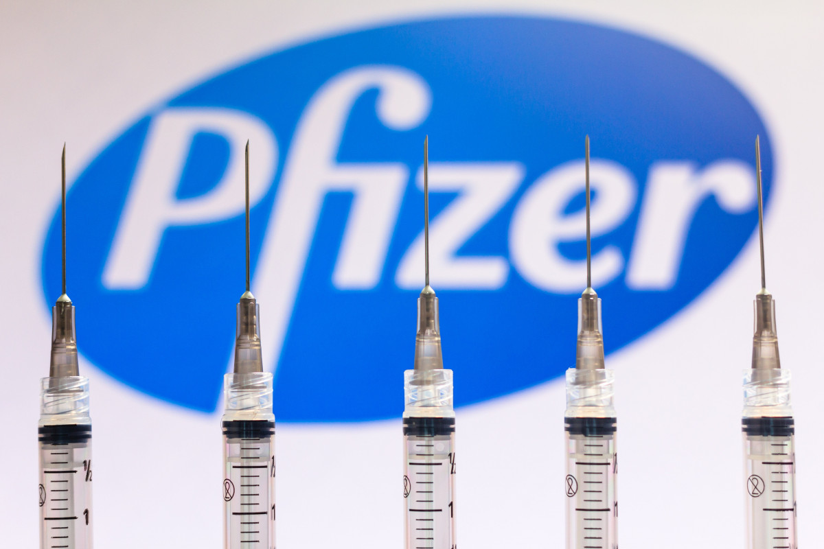 Imaxe de arquivo dunha vacúas fronte ao logo da farmacéutica Pfizer.