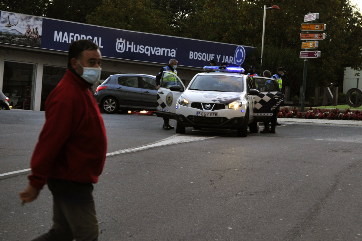 Un home pasa á beira de varios axentes durante un control de mobilidade nunha vía do Carballiño, Ourense, Galicia (España), ao 15 de outubro de 2020. Desde hoxe, a Xunta limita as entradas e sa